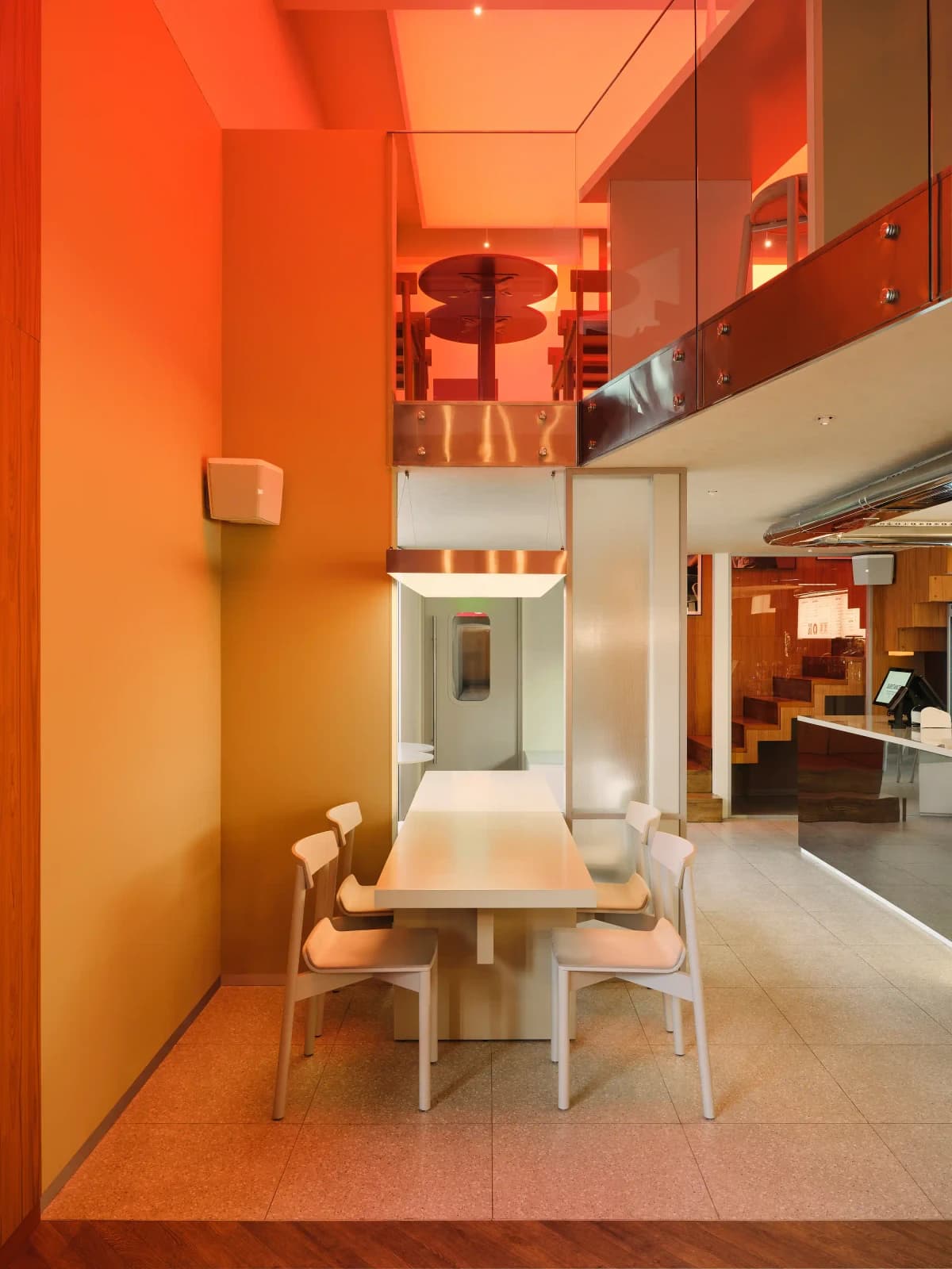 Столик в нише с оранжевыми стенами и видом на второй этаж