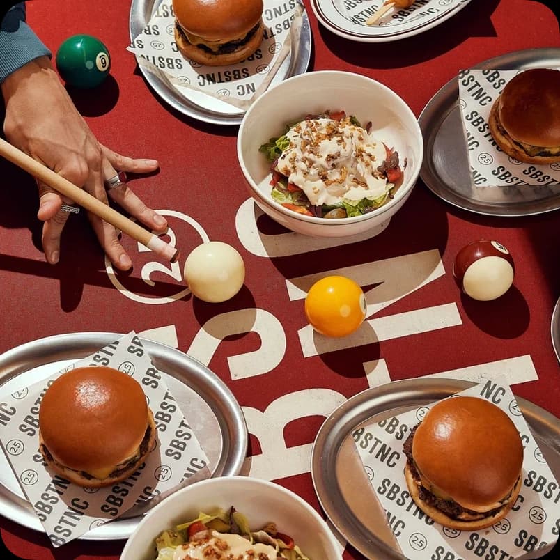 Стол с бургерами, салатами и напитками на красном бильярдном столе